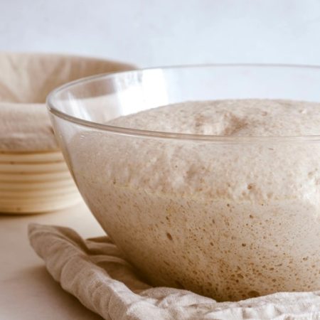 Skleněná mísa s kynutým těstem a ošatka na pečivo