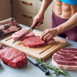 Červené maso: Proč patří do zdravého jídelníčku i při hubnutí a kolik ho jíst? Fit žena krájí a připravuje hovězí maso a jiné druhy červeného masa